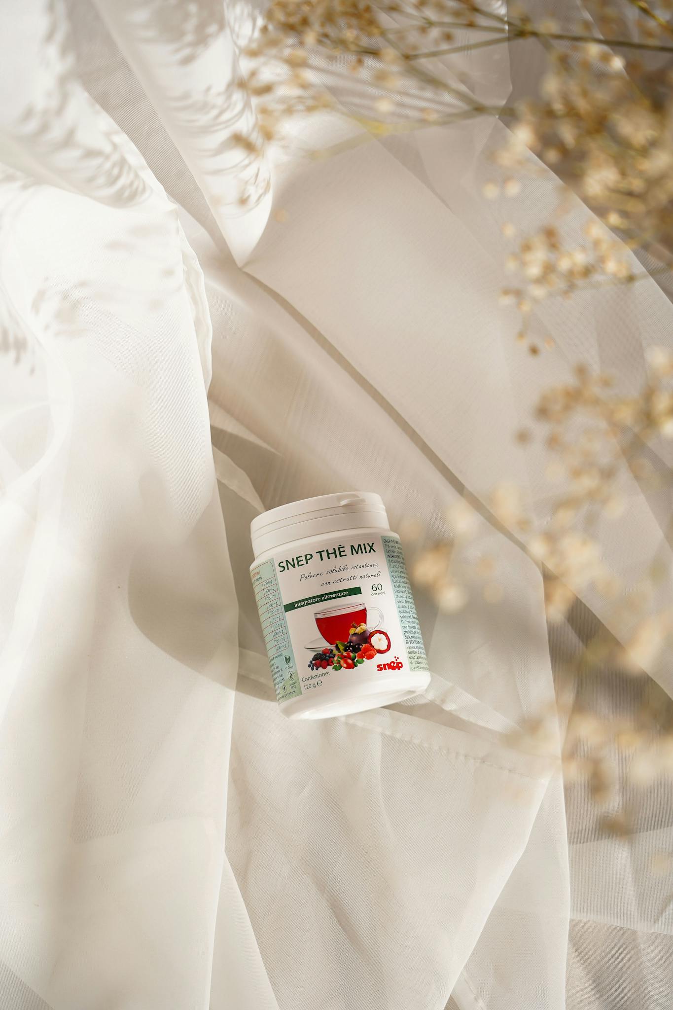 A container of herbal supplement resting on soft white fabric in a warm, elegant setting.